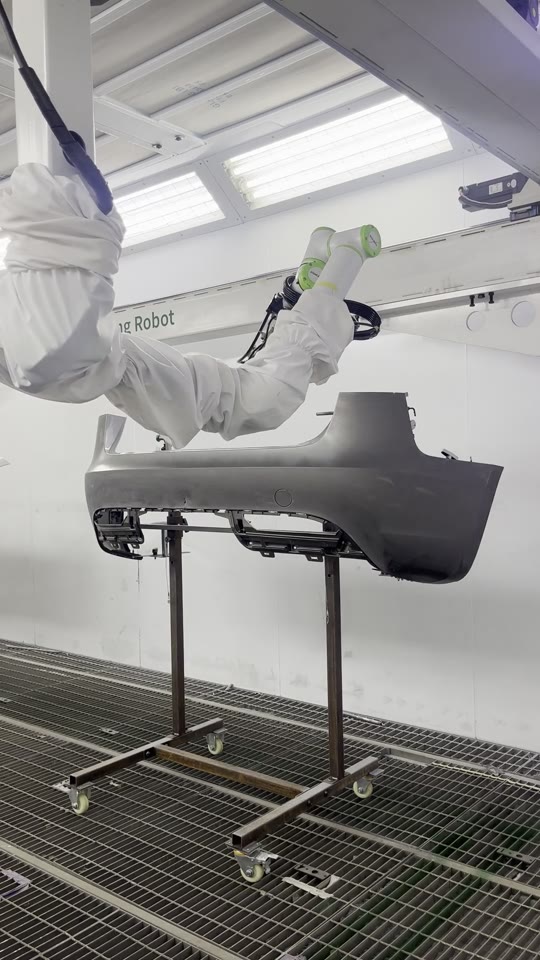 Close-up of the NST robot arm spraying in the booth